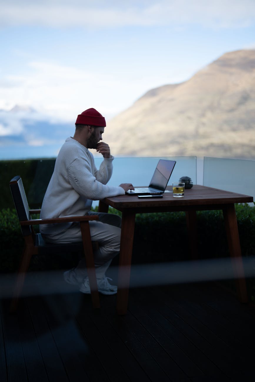 man working on laptop with mountain view in queenstown