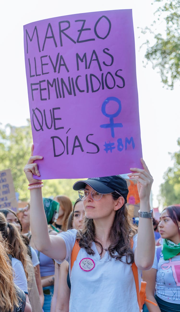 young woman carrying a purple banner with a slogan in spanish at a womens day rally in mexico city